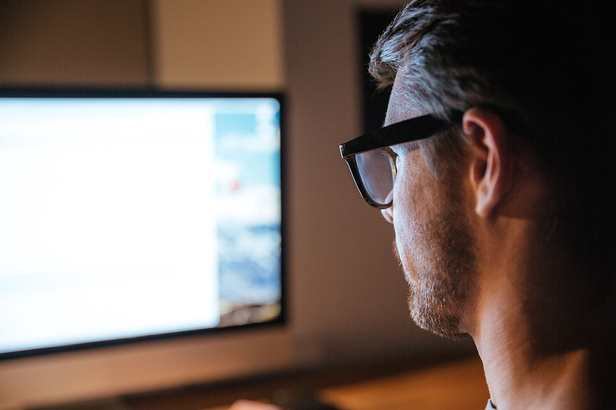 Concentrated man sitting and looking at screen of monitor Man purchasing tax software