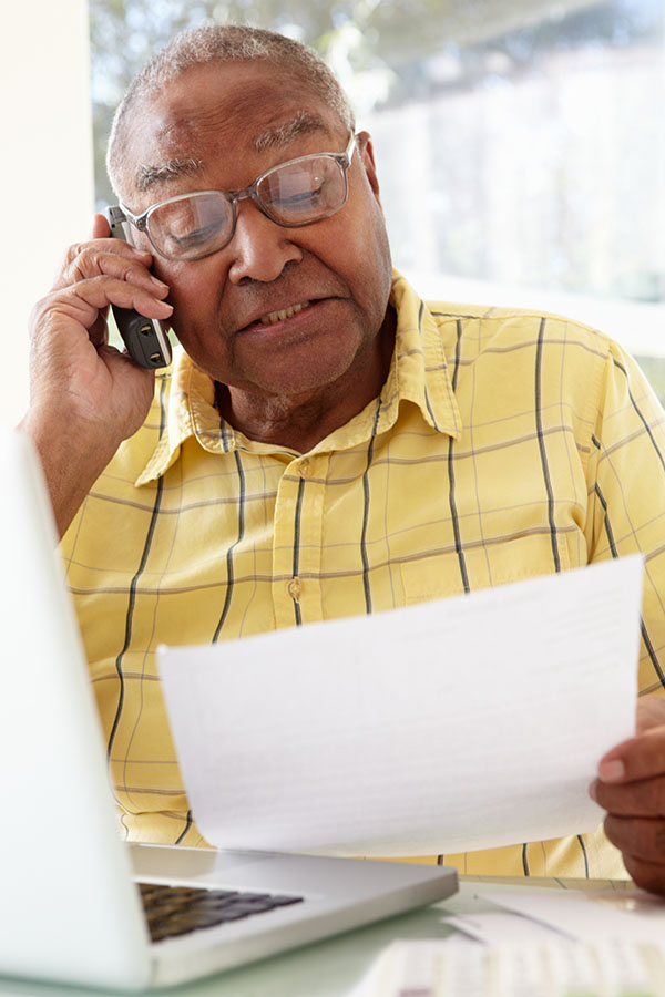 Senior Man On Phone Using Laptop At Home Tax Professional